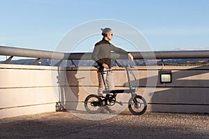 Young man using a folding electric bicycle to move in the city where he lives and be greener with the environment