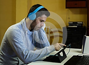 Young man using his mobile, tablet, laptop and headphones