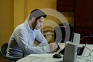 Young man using his mobile, tablet, laptop and headphones