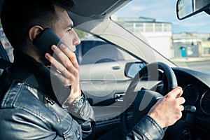 Young man using his phone while driving the car. Dangerous driving