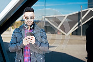 Young man using his phone and listening music close up isolated happy outdoor