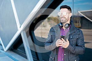 Young man using his phone and listening music close up isolated happy outdoor