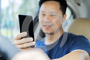 Young man using his smartphone behind the wheel