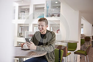 Young man using his smartphone in a modern university cafe