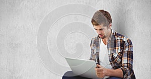 Young man using laptop against wall