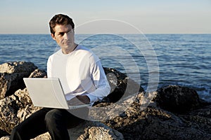 Young man using laptop at beach