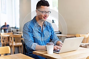 Young man using laptop at cafe