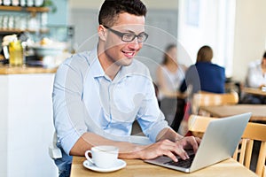 Young man using laptop at cafe