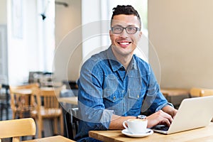 Young man using laptop at cafe