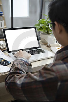 Young man using laptop and checking balance and costs at home.