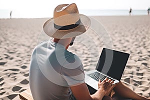 Young man using laptop computer on a beach. Freelance work concept
