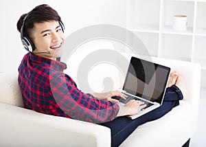 Young man using laptop computer with headset