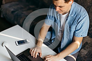 Young man using laptop and headphones at home.