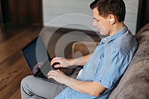 Young man using laptop and headphones at home.