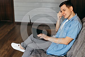 Young man using laptop and headphones at home.