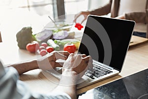 Young man working using laptop in the kitchen