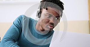 Young man using laptop and listening music on headphones in bedroom