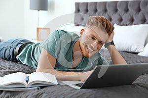 Young man using laptop while lying on bed