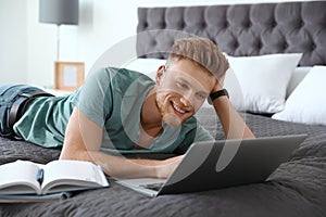 Young man using laptop while lying on bed