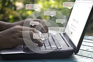 Young man using laptop.Man`s hand hold smartphone play social media with communication icon.