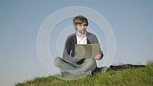 Young Man Using Laptop Outdoors Sitting On The Grass In Park