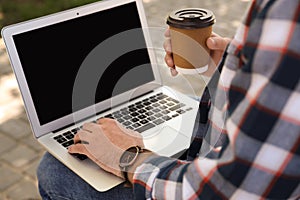 Young man using laptop outdoors. Space for text