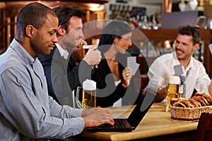 Young man using laptop at pub