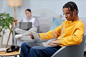 Young man using laptop while sitting on sofa in office lounge