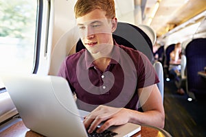 Young Man Using Laptop On Train Journey