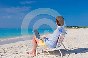 Young man using laptop on tropical beach