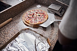 Young man using metal pizza peel in pizzeria