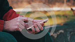 Young man using a mobile phone on a bench in the city park