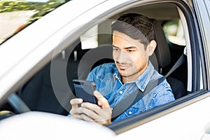 Young man using mobile phone in a car