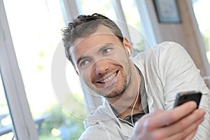 Young man using mobile phone and earphones