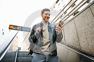 Young man using mobile phone while going down escalator outdoors
