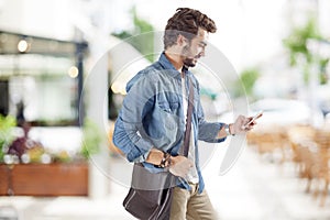 Young man using mobile phone in street