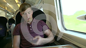 Young Man Using Mobile Phone On Train Journey