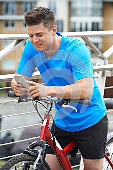 Young Man Using Mobile Phone Whilst Out On Cycle Ride