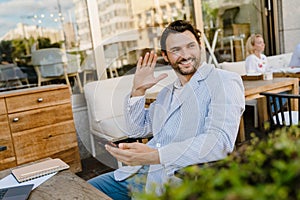 Young man using mobile phone while working with laptop at cafe