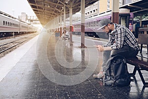 Young man using mobile smart phone checking train timetable at train station platform. Asian traveler text message with cellphone.