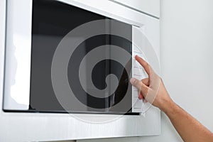 Young man using modern microwave oven