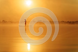 Young man using paddle board for swimming at lake