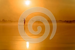 Young man using paddle board for swimming at lake