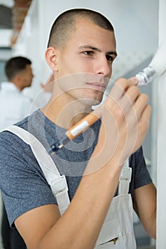 Young man using paint roller while painting wall at home