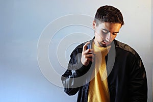 Young man using perfume or cologne on a gray background