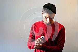 Young man using perfume or cologne on a gray background