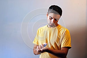 Young man using perfume or cologne on a gray background