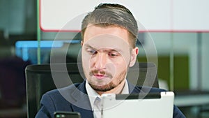 Young Man Using a Phone and a Tablet in the Office