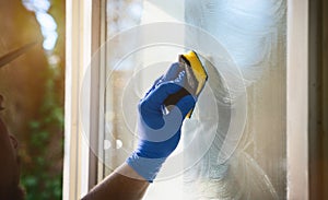 Young man is using a rag and squeegee while cleaning windows.