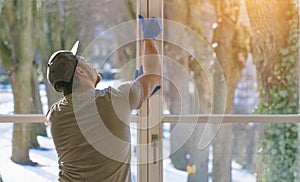 Young man is using a rag and squeegee while cleaning windows.